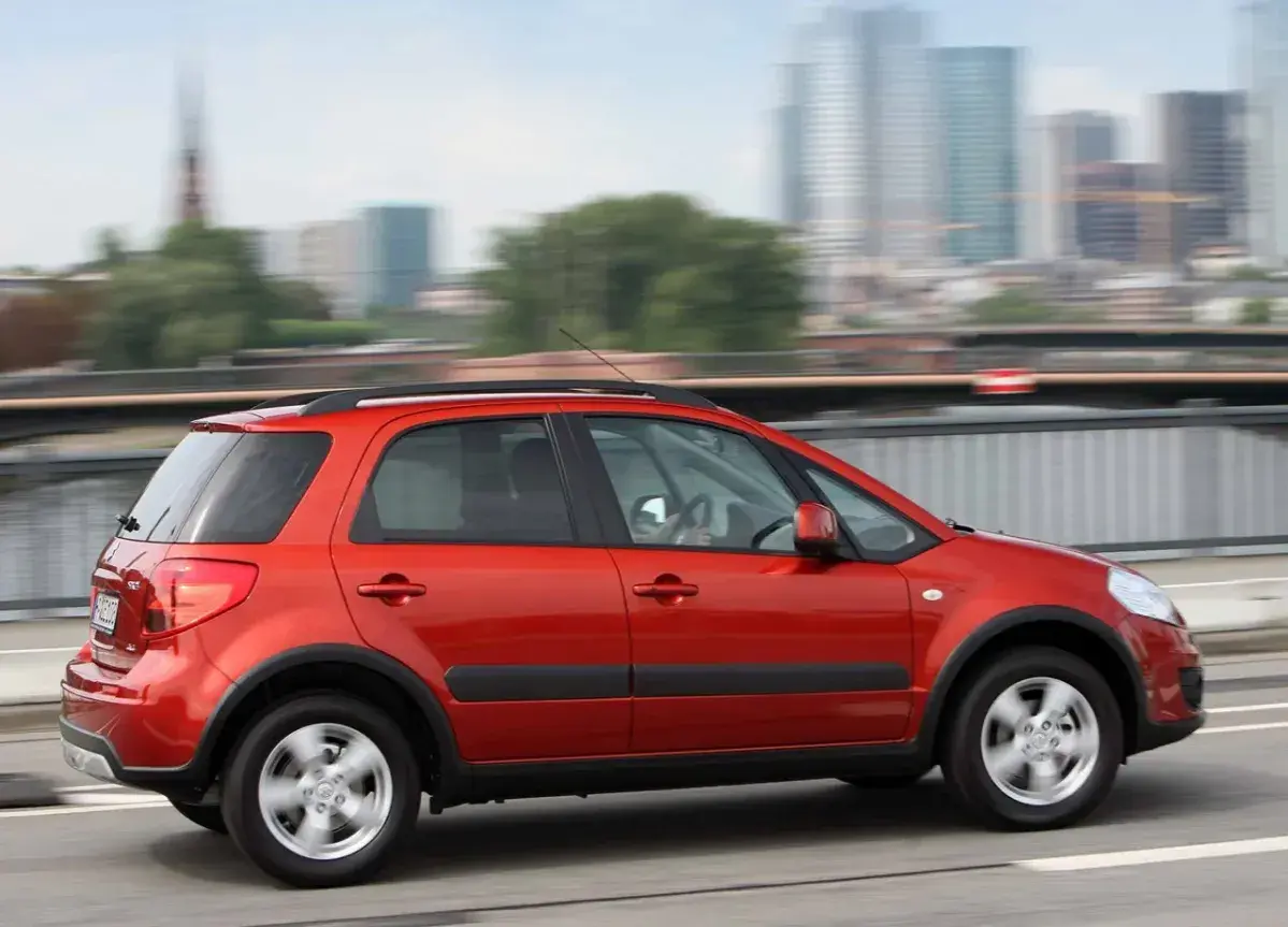 Czerwony Suzuki SX4 w ruchu miejskim. Wiele osób chwali ten model, a jego opinie są pozytywne.