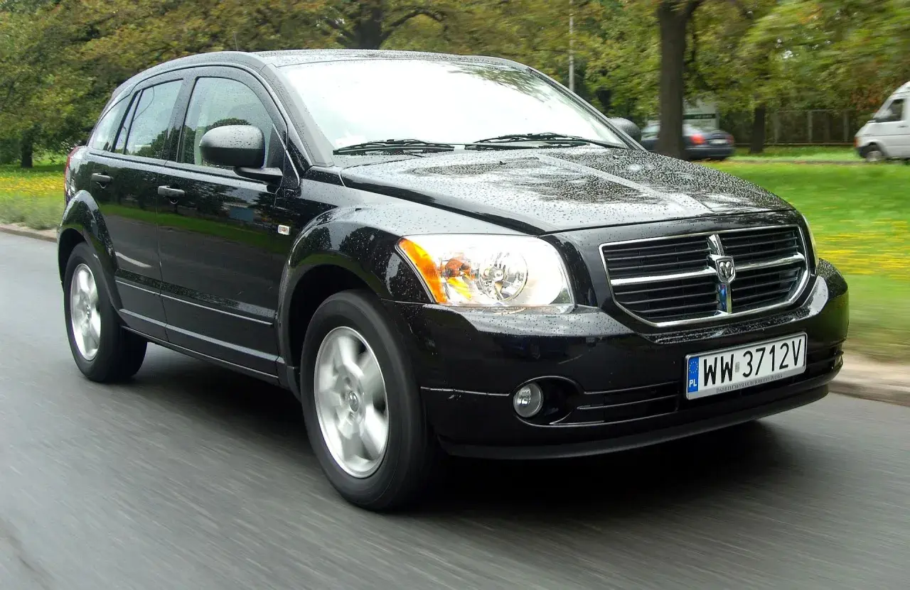 Czarny Dodge Caliber w ruchu, na mokrej drodze. Wiele osób szuka dodge caliber opinie, ten samochód wygląda na solidny.