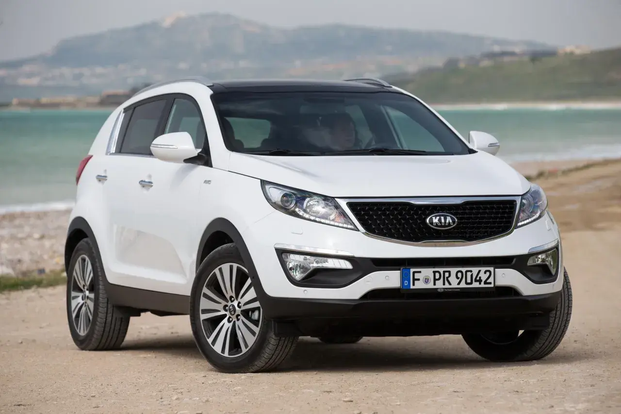 Biały Kia Sportage 2014 na plaży, gotowy na przygodę nad morzem.