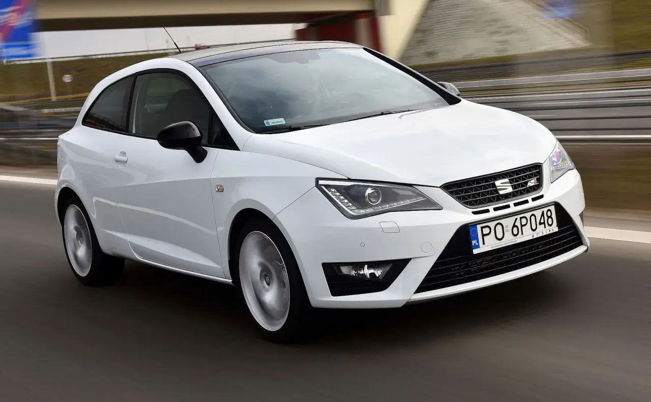 Biały Seat Ibiza 1.4 benzyna pędzi po drodze, z czarnym dachem i felgami.