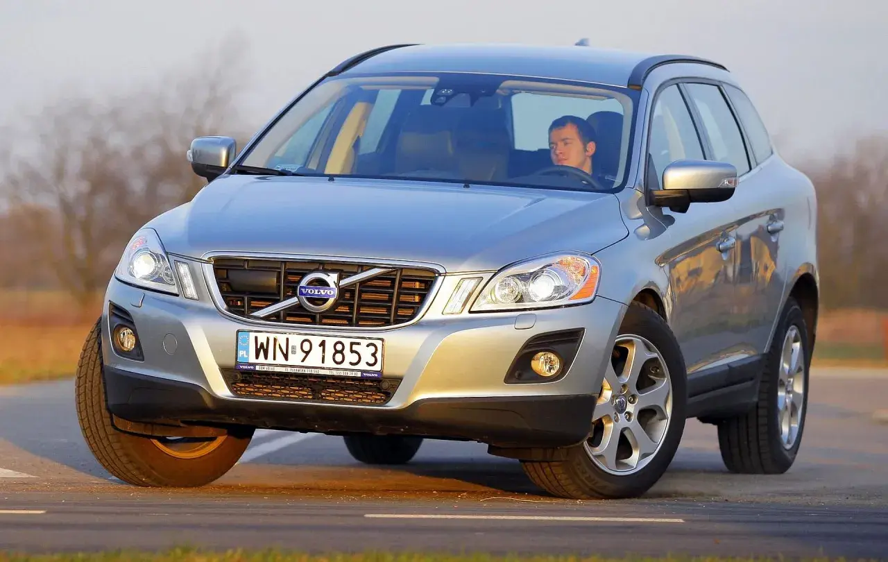 Srebrne Volvo XC60 z mężczyzną za kierownicą na drodze. Wiele osób szuka **volvo xc60 opinie** przed zakupem.