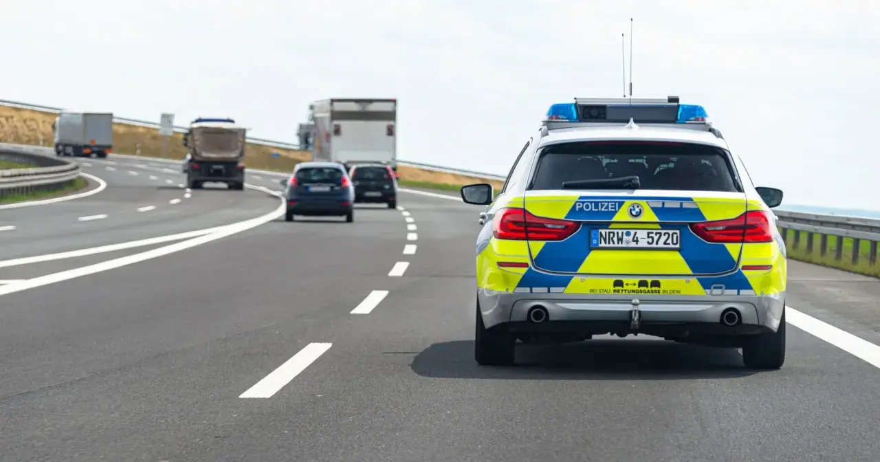Niemieckie autostrady: radiowóz policyjny z włączonymi sygnałami świetlnymi jedzie za innymi pojazdami.