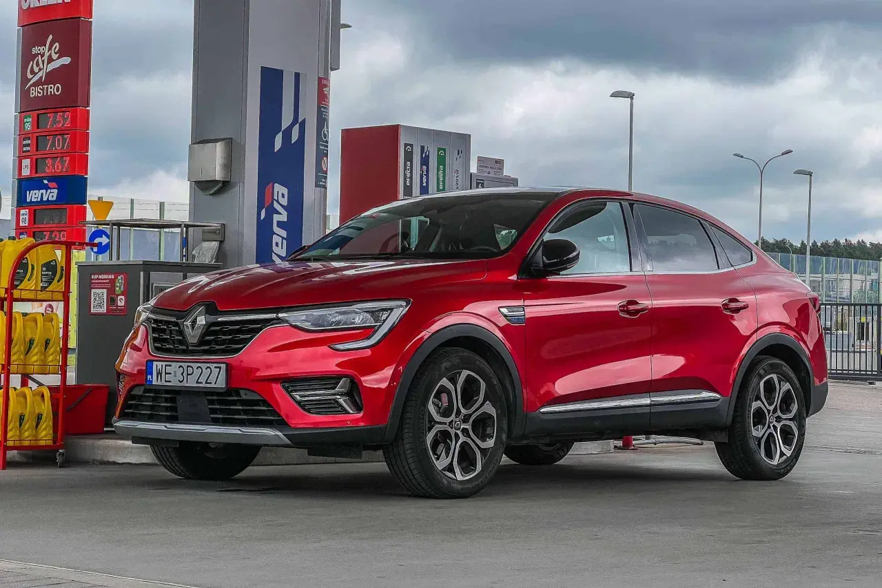 Czerwony Renault Arkana na stacji paliw. Wiele osób szuka **Renault Arkana opinie** przed zakupem.