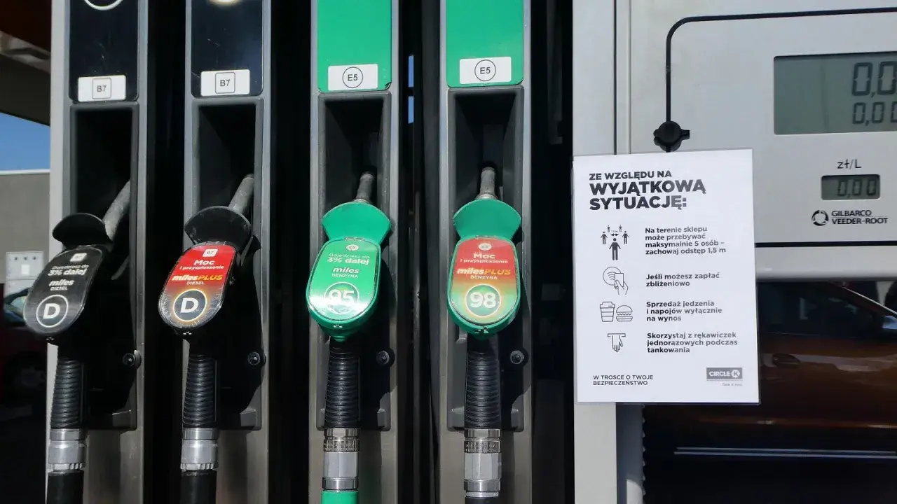 Dwa dystrybutory paliwa, jeden z oznaczeniem 95, drugi z 98. Obok tabliczka z zasadami bezpieczeństwa.