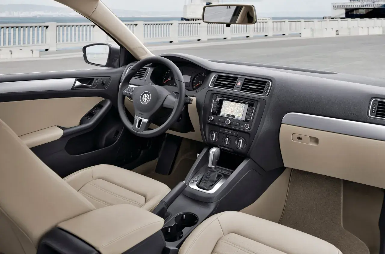 Wnętrze VW Jetta MK6 z jasną tapicerką, nawigacją i automatyczną skrzynią biegów.