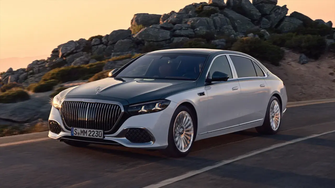 Elegancki, dwukolorowy Mercedes-Maybach sunie po górskiej drodze o zachodzie słońca.