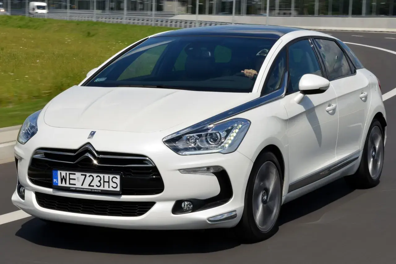 Biały Citroen DS5 na drodze. Kierowca za kierownicą. Wiele osób szuka pozytywnych **citroen ds5 opinie** przed zakupem.