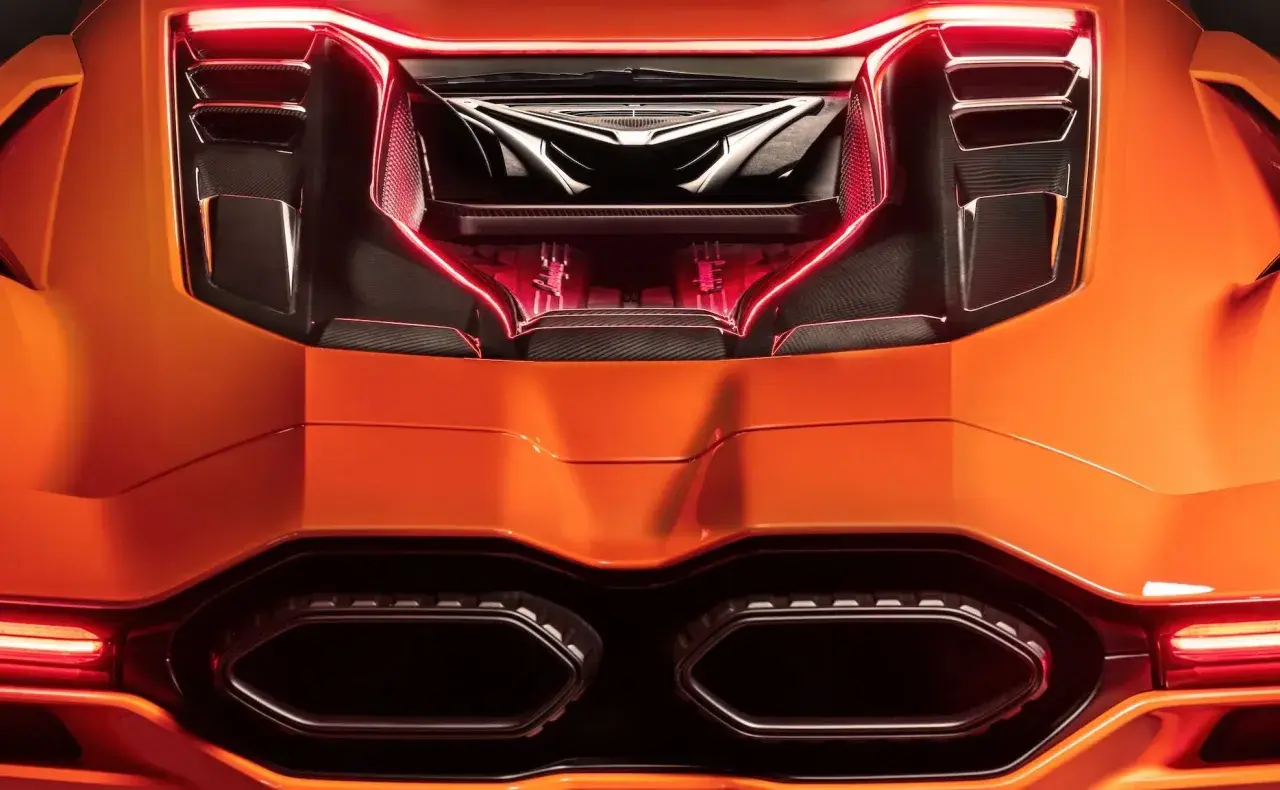 Pomarańczowy Lamborghini Revuelto z widocznym silnikiem i czerwonym podświetleniem.