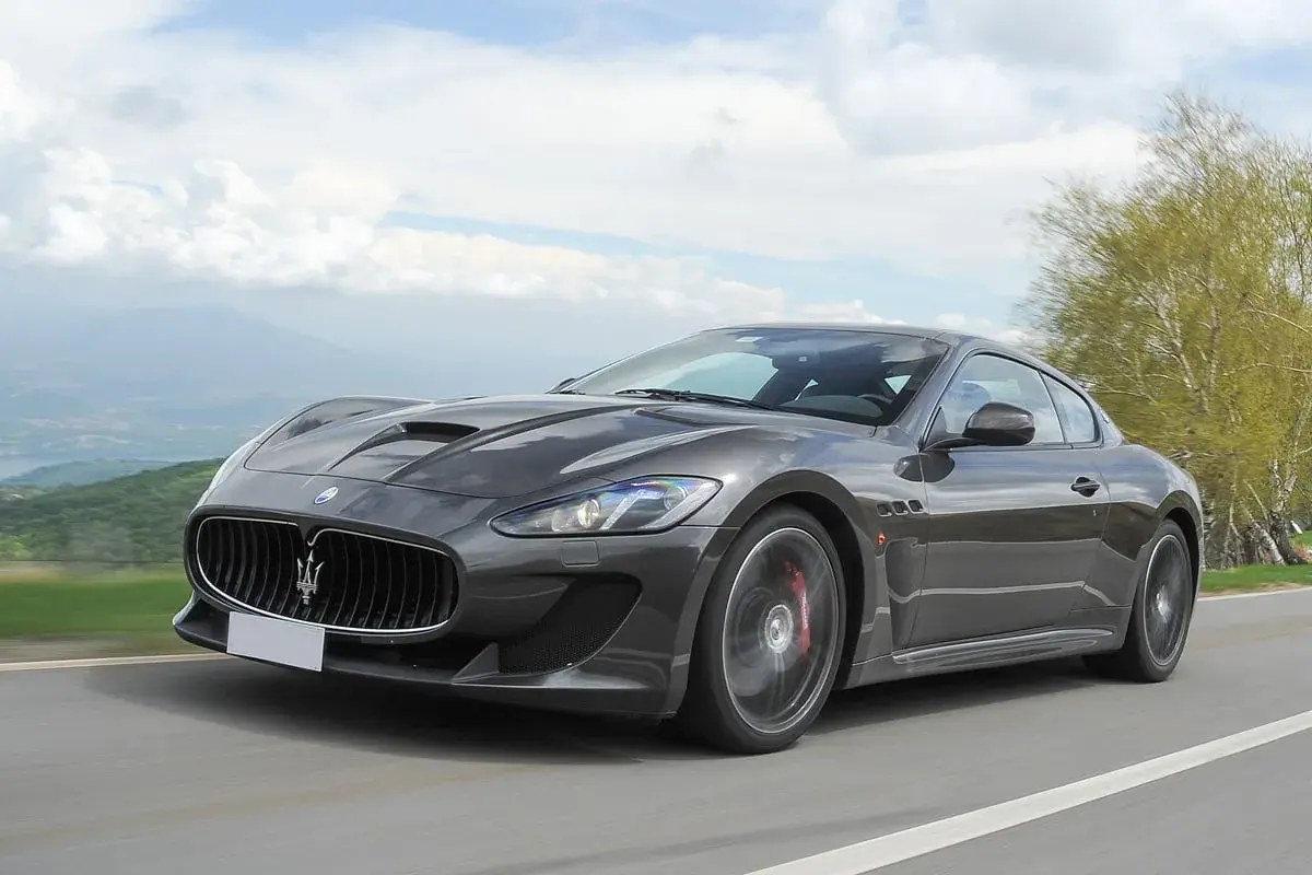 Szary Maserati GranTurismo na krętej drodze. Marzysz o takim aucie? Sprawdź aktualną maserati cena i spełnij marzenie.