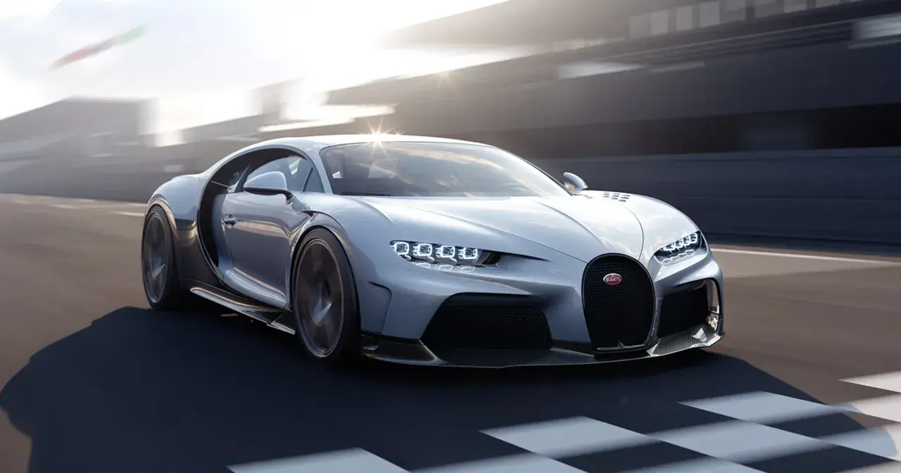 Srebrny Bugatti Chiron Super Sport pędzi po torze wyścigowym, jego światła LED błyszczą w słońcu.