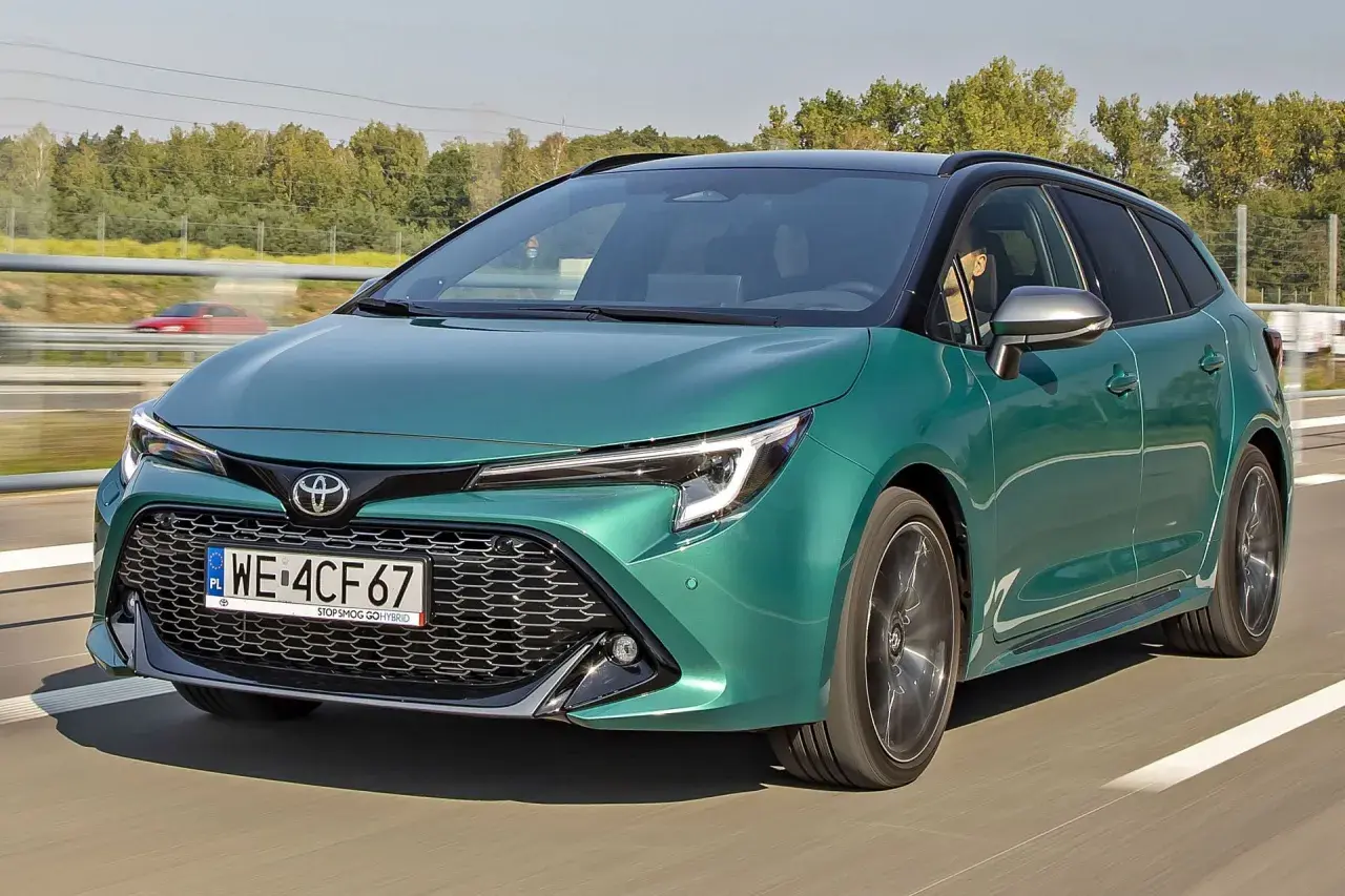 Zielona Toyota Corolla kombi jedzie po drodze, za nią widać drzewa i inny samochód.