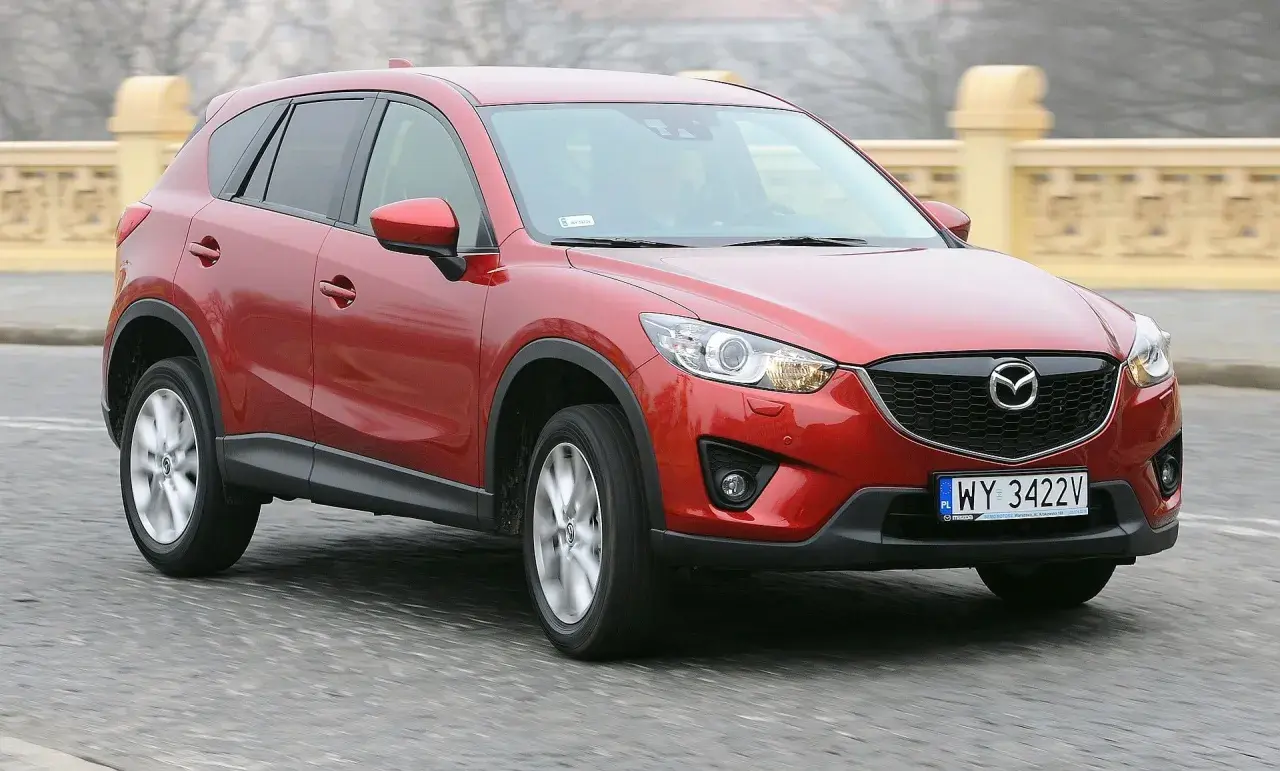 Czerwona Mazda CX-5 na drodze, z widocznym grillem i tablicą rejestracyjną.