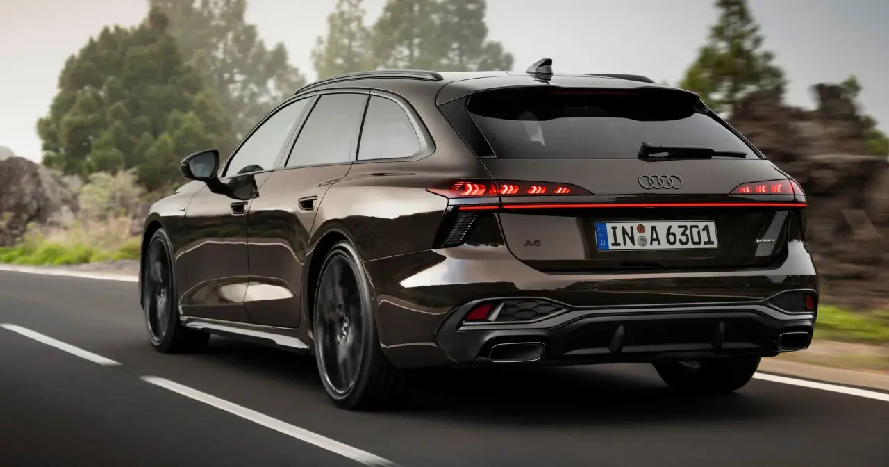 Elegancki Audi Avant w brązowym kolorze jedzie po krętej drodze wśród drzew.