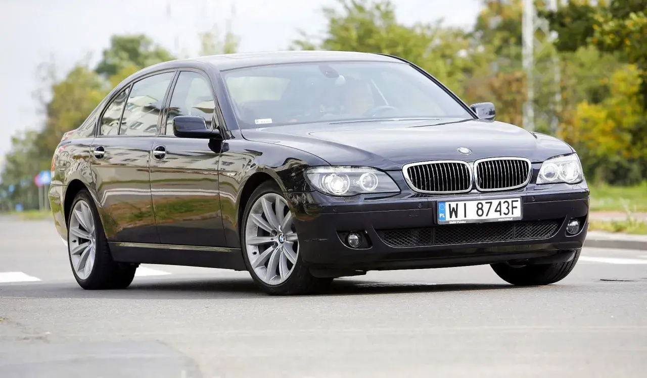 Eleganckie czarne BMW 730d na polskich tablicach WI 8743F jedzie po drodze, otoczone zielenią.