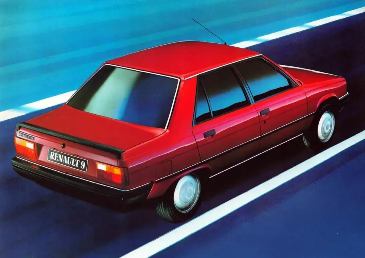 Czerwony Renault 9 pędzi po drodze, odbijając się w niebieskim tle.
