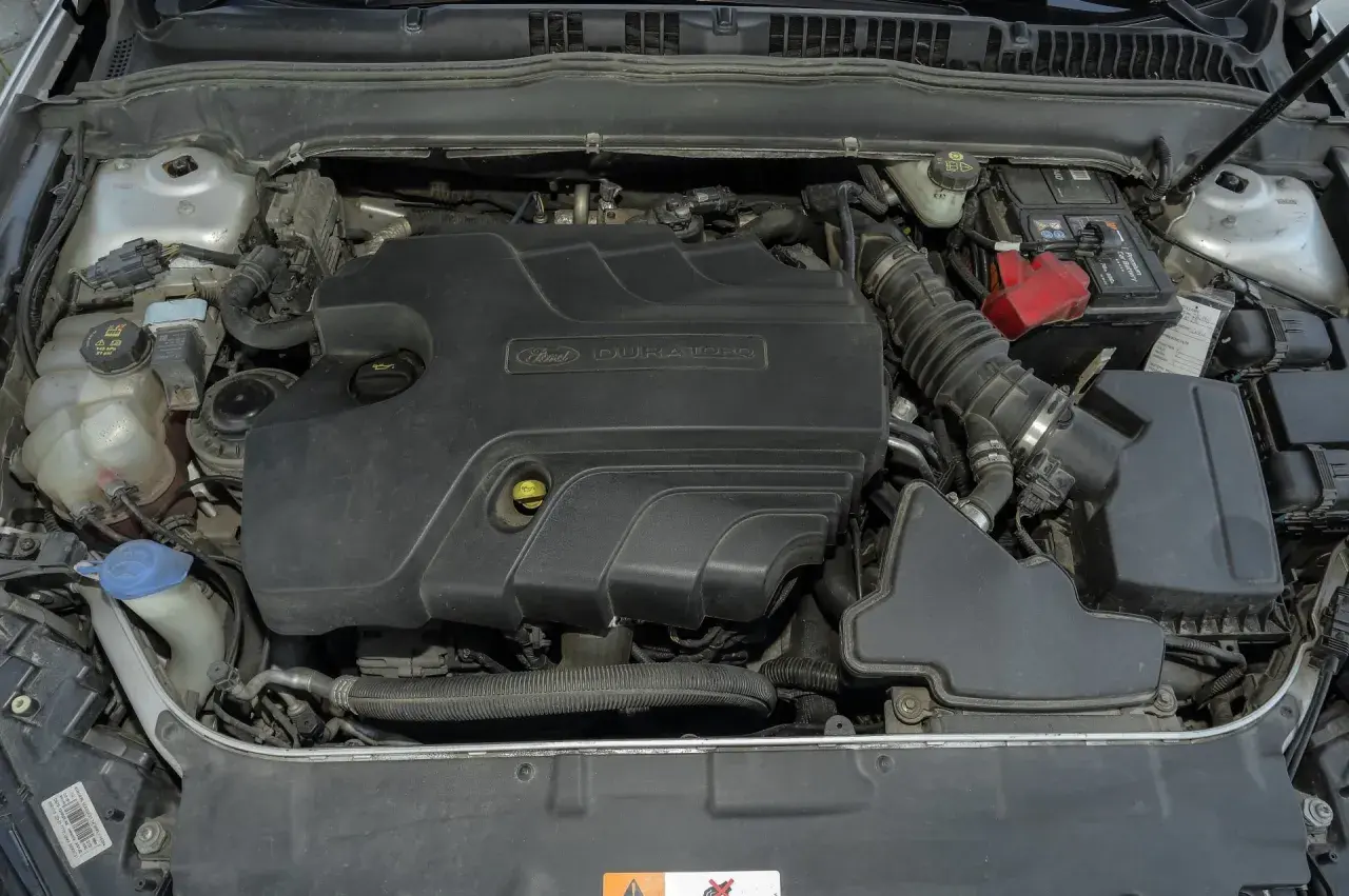 Silnik Duratorq 2.0 TDCI w Fordzie Mondeo MK5. Widoczny akumulator, zbiornik płynu chłodniczego i elementy układu dolotowego.