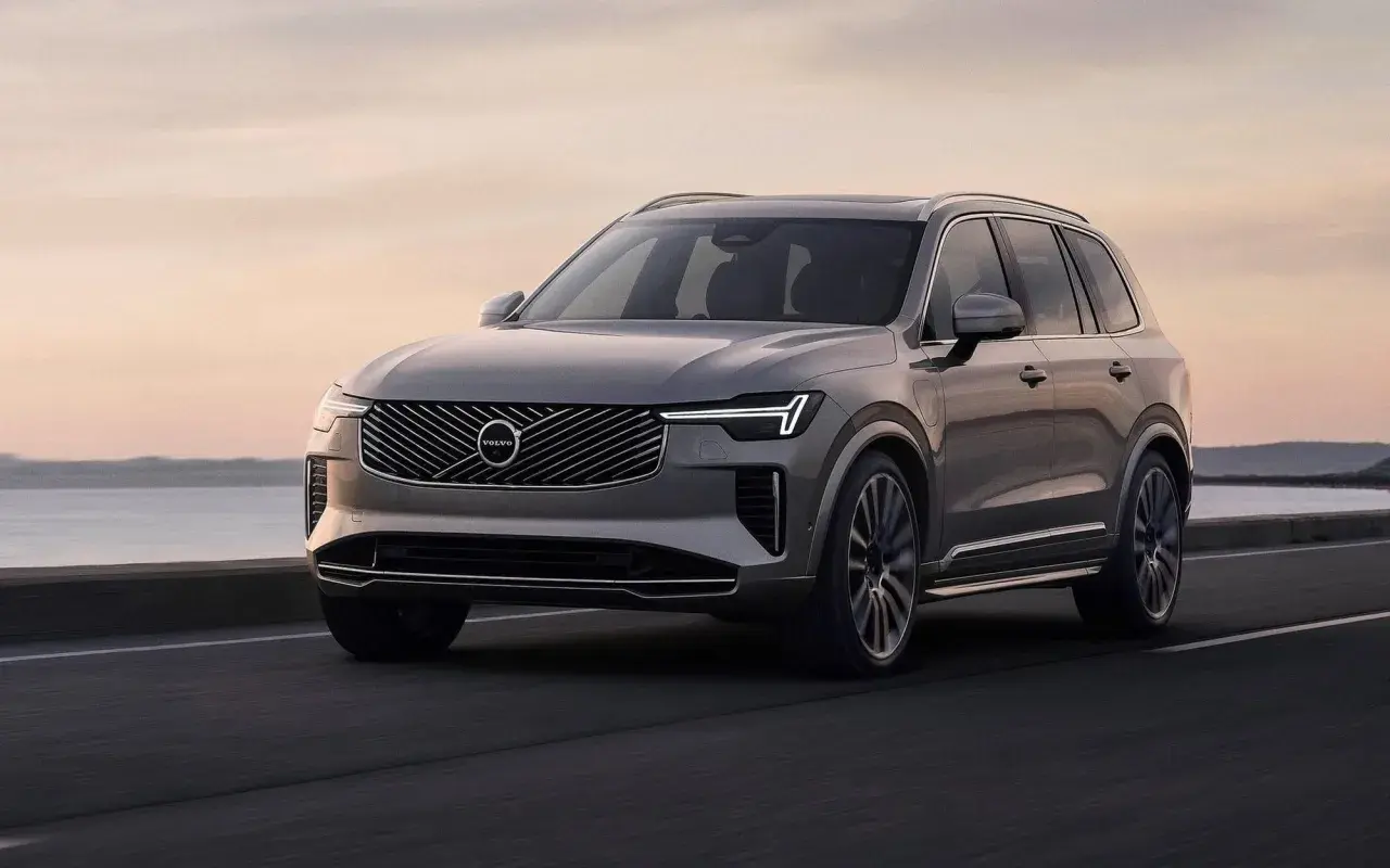 Szary Volvo XC90 w ruchu, z pięknym zachodem słońca w tle. Wiele osób szuka volvo xc90 opinie przed zakupem.