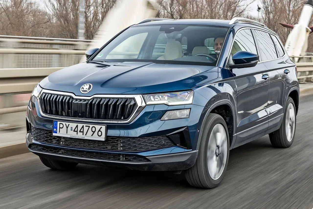 Niebieski Skoda Karoq jedzie po moście. Sprawdź aktualną skoda karoq cena i wybierz swój wymarzony SUV.