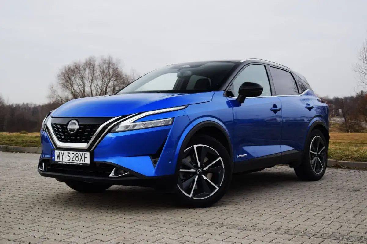 Niebieski Nissan Qashqai e-POWER na brukowanej nawierzchni. Wiele osób szuka nissan qashqai opinie przed zakupem.