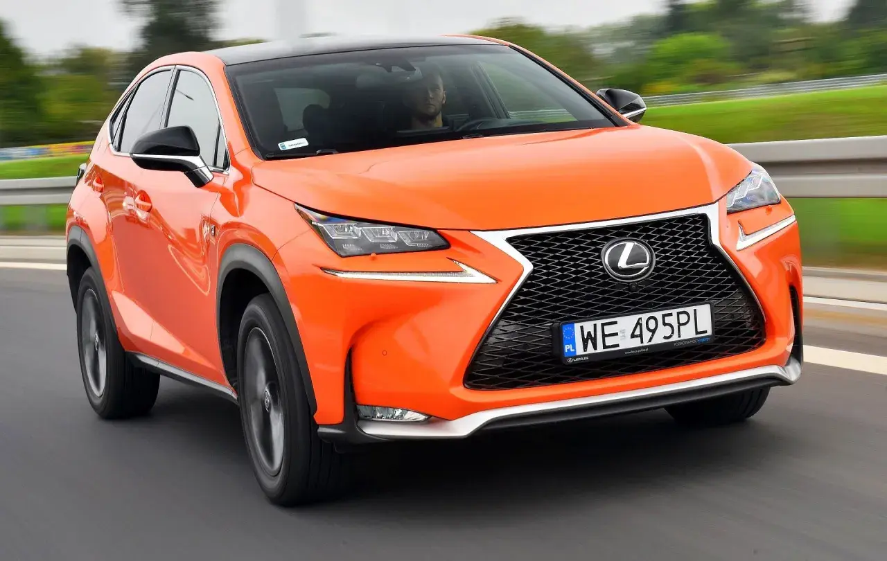 Pomarańczowy Lexus NX300h pędzi po drodze, jego dynamiczna sylwetka i nowoczesne linie przyciągają wzrok.