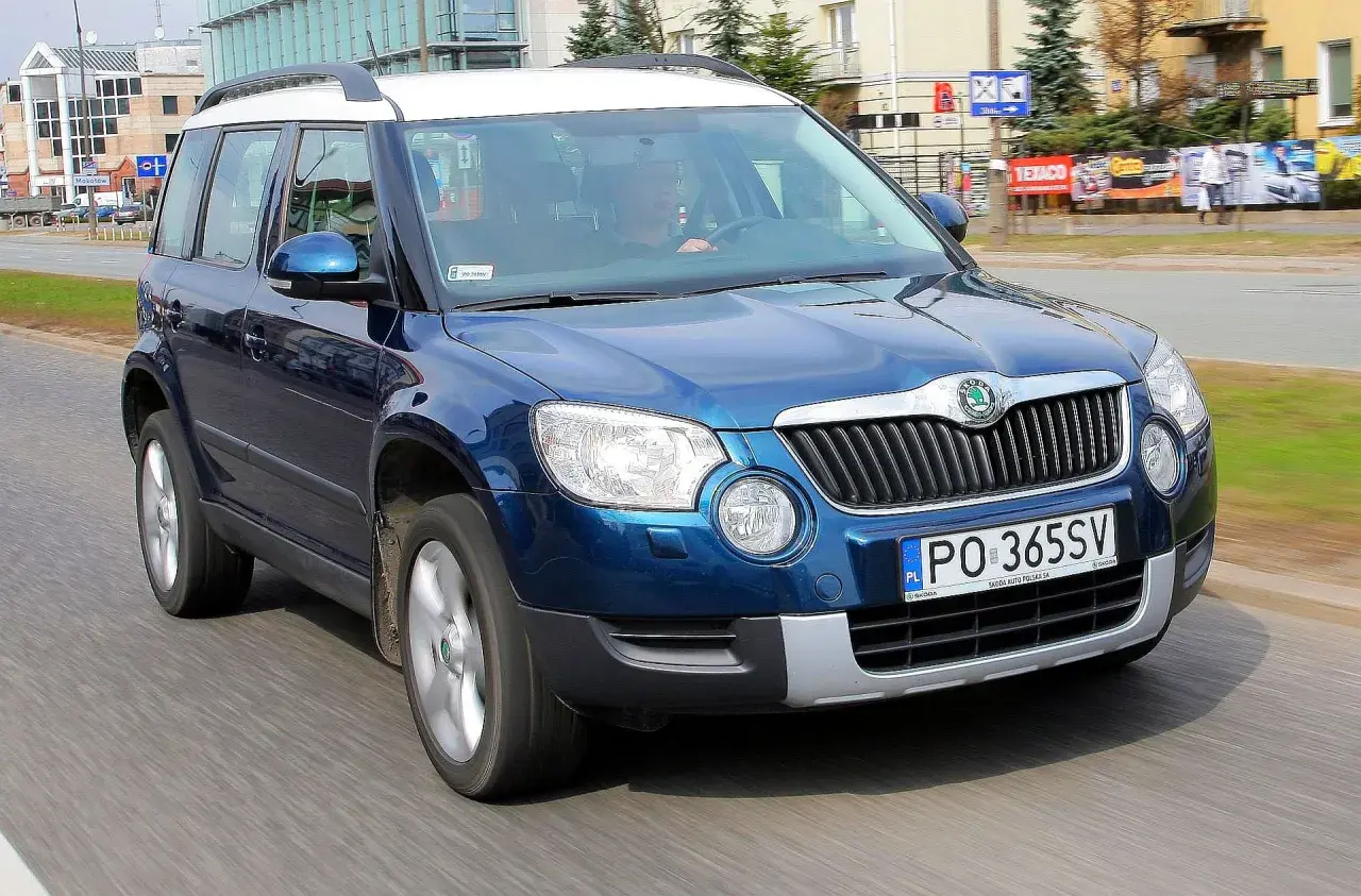 Niebieska Skoda Yeti na drodze. Kierowca w środku. Wiele pozytywnych skoda yeti opinie o tym modelu.