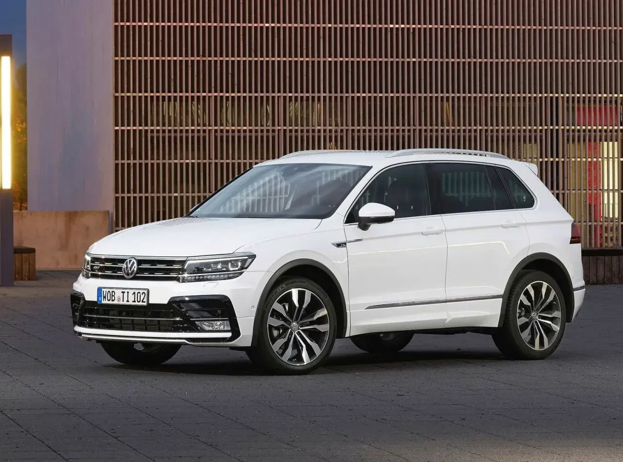 Biały Volkswagen Tiguan na tle nowoczesnej fasady. Wiele osób szuka **volkswagen tiguan opinie** przed zakupem.