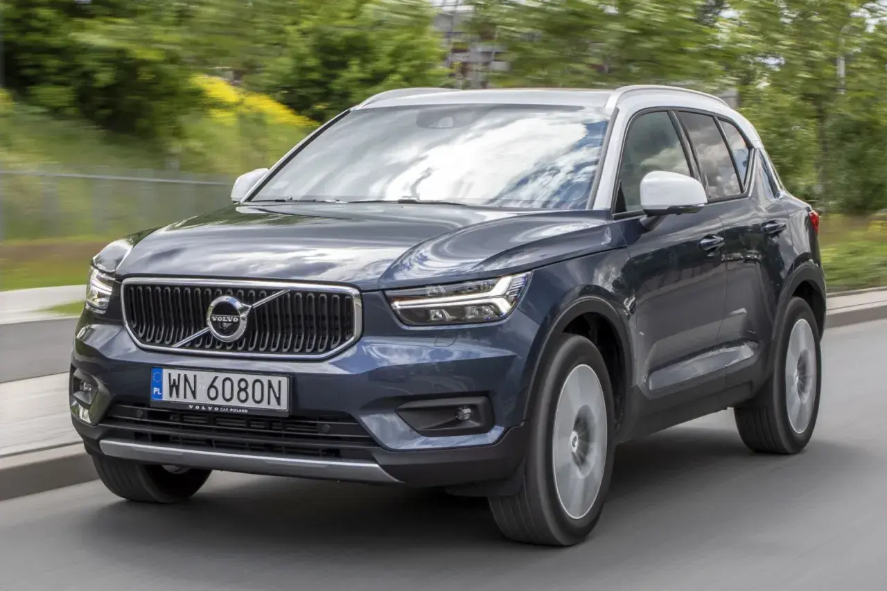 Ciemnogranatowy Volvo XC40 z białym dachem jedzie po drodze. Wiele osób szuka volvo xc40 opinie przed zakupem.