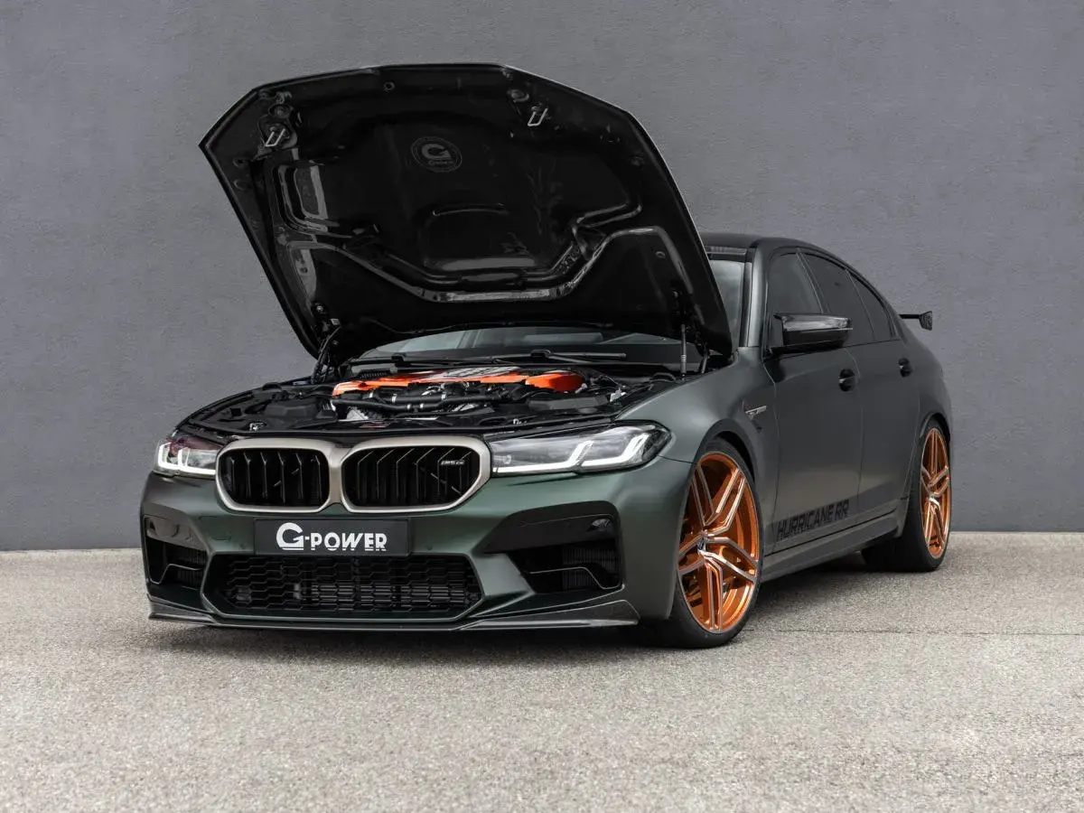 Mocarny BMW M5 G Power z otwartą maską, prezentujący pomarańczowy silnik i miedziane felgi.