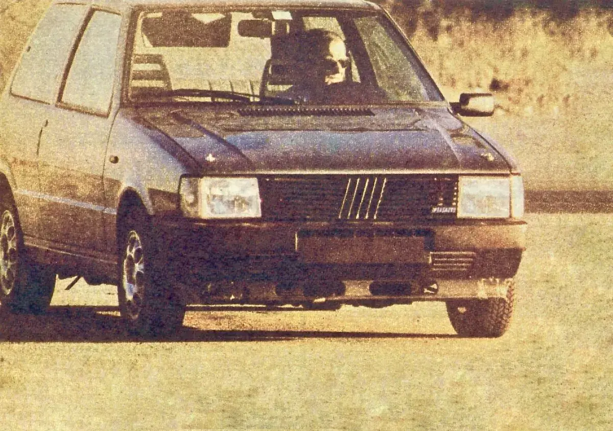 Ciemny Fiat Uno Turbo z kierowcą za kierownicą, gotowy do jazdy.