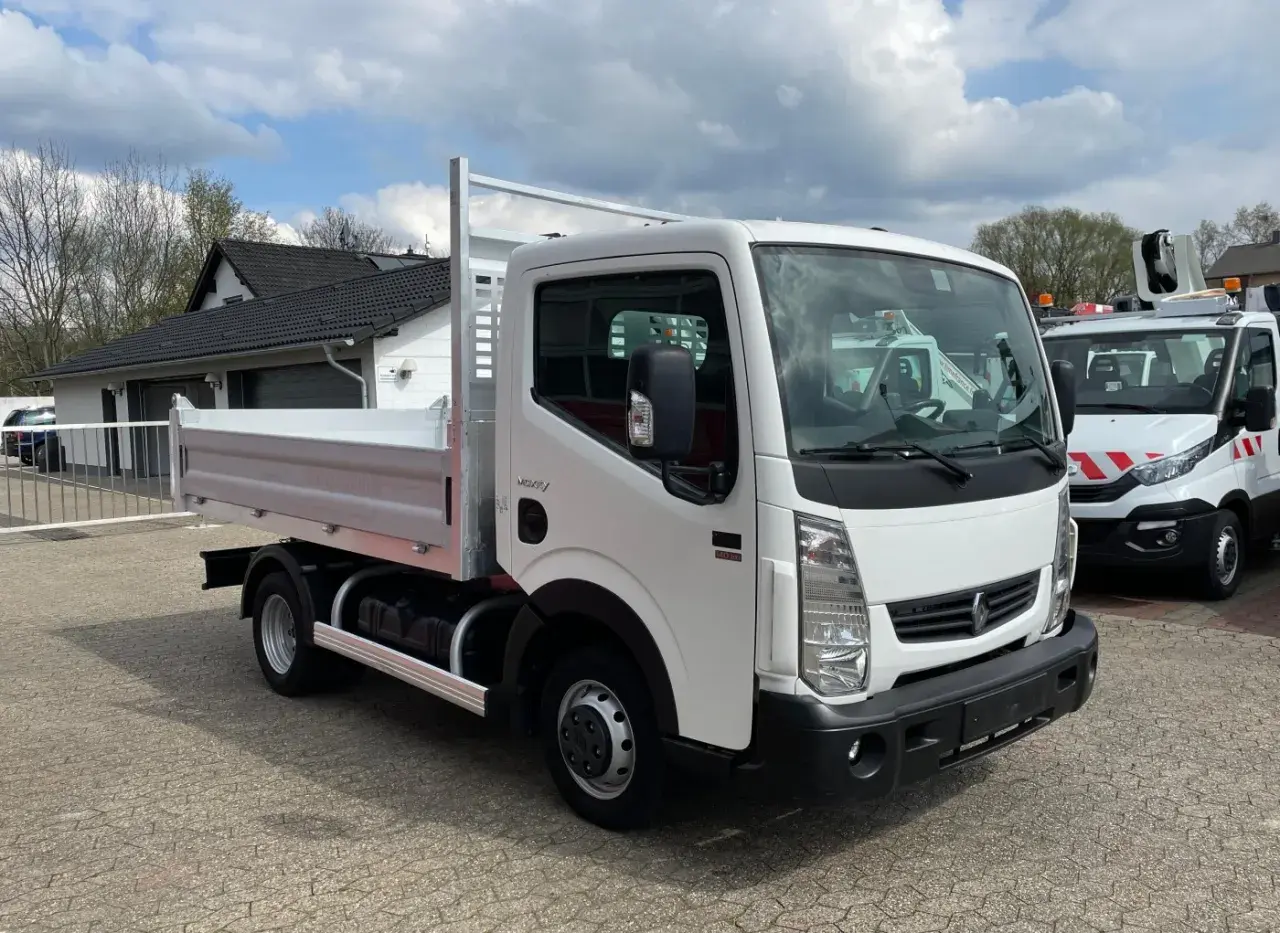 Biały Renault Maxity z otwartą skrzynią ładunkową stoi na placu.