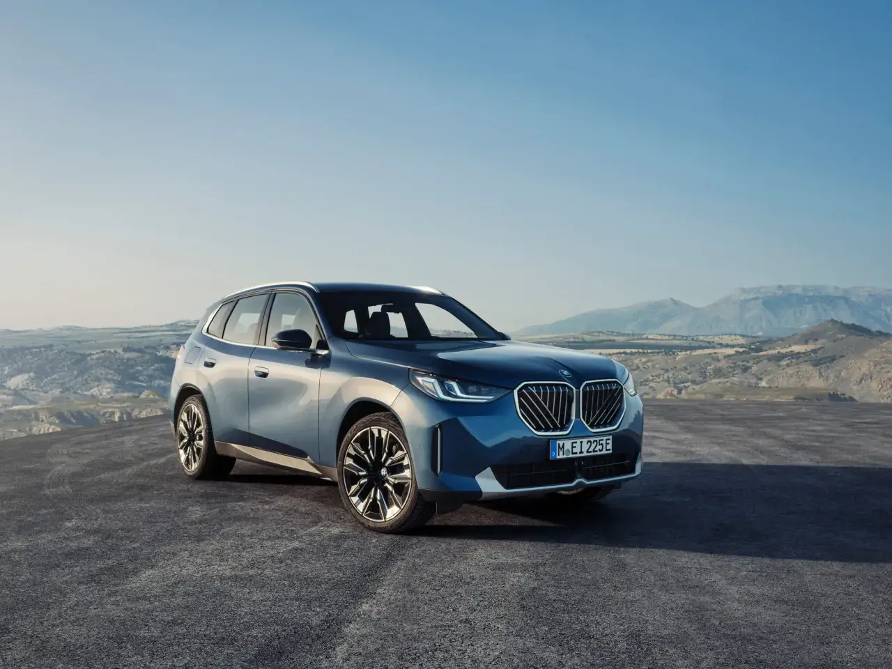 Nowy, błękitny BMW X3 2024 na tle górskiego krajobrazu.