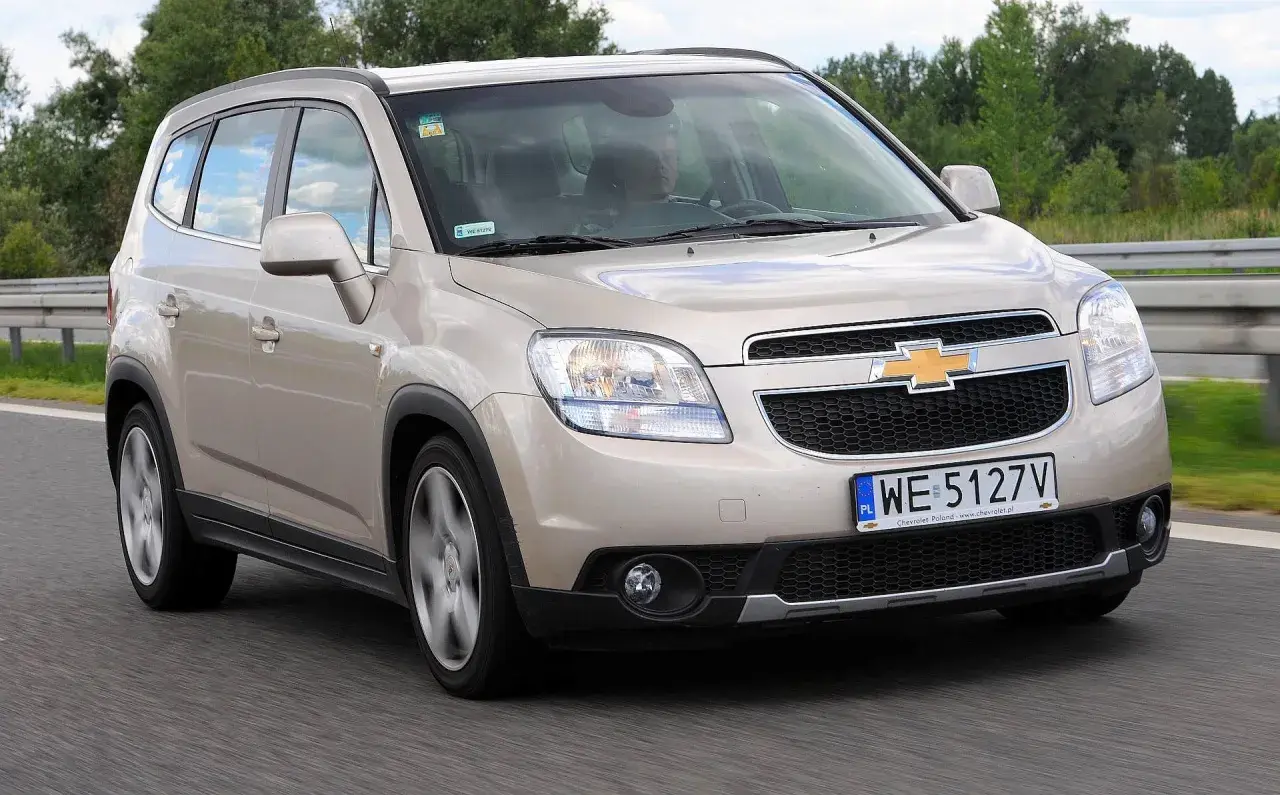 Złoty Chevrolet Orlando 1.8 benzyna na drodze. Rodzinny minivan w ruchu, z widocznym kierowcą.