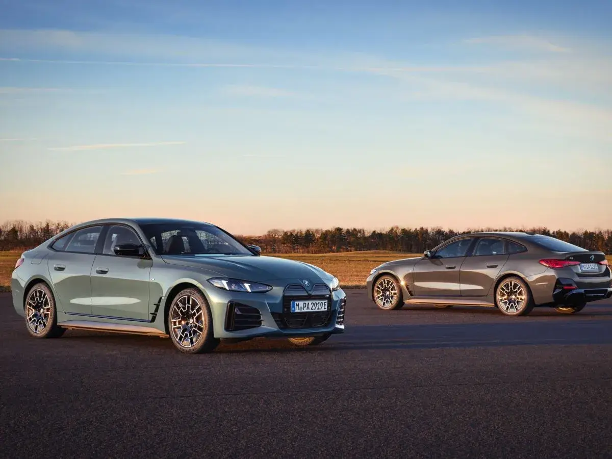 Dwa eleganckie BMW Gran Coupe, jedno zielone, drugie brązowe, stoją na asfalcie o zachodzie słońca.