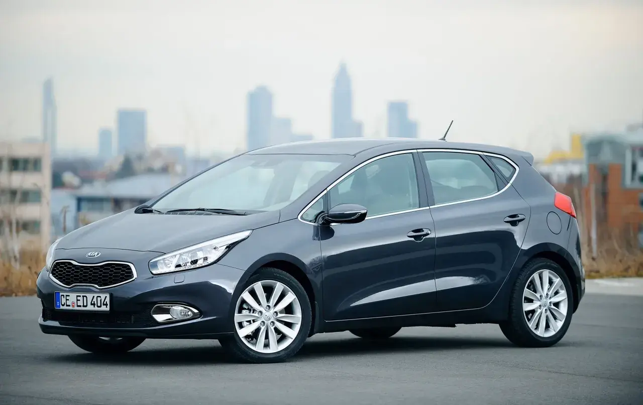 Ciemnoszary Kia Ceed 1.6 CRDi z eleganckimi felgami stoi na tle miejskiej panoramy.