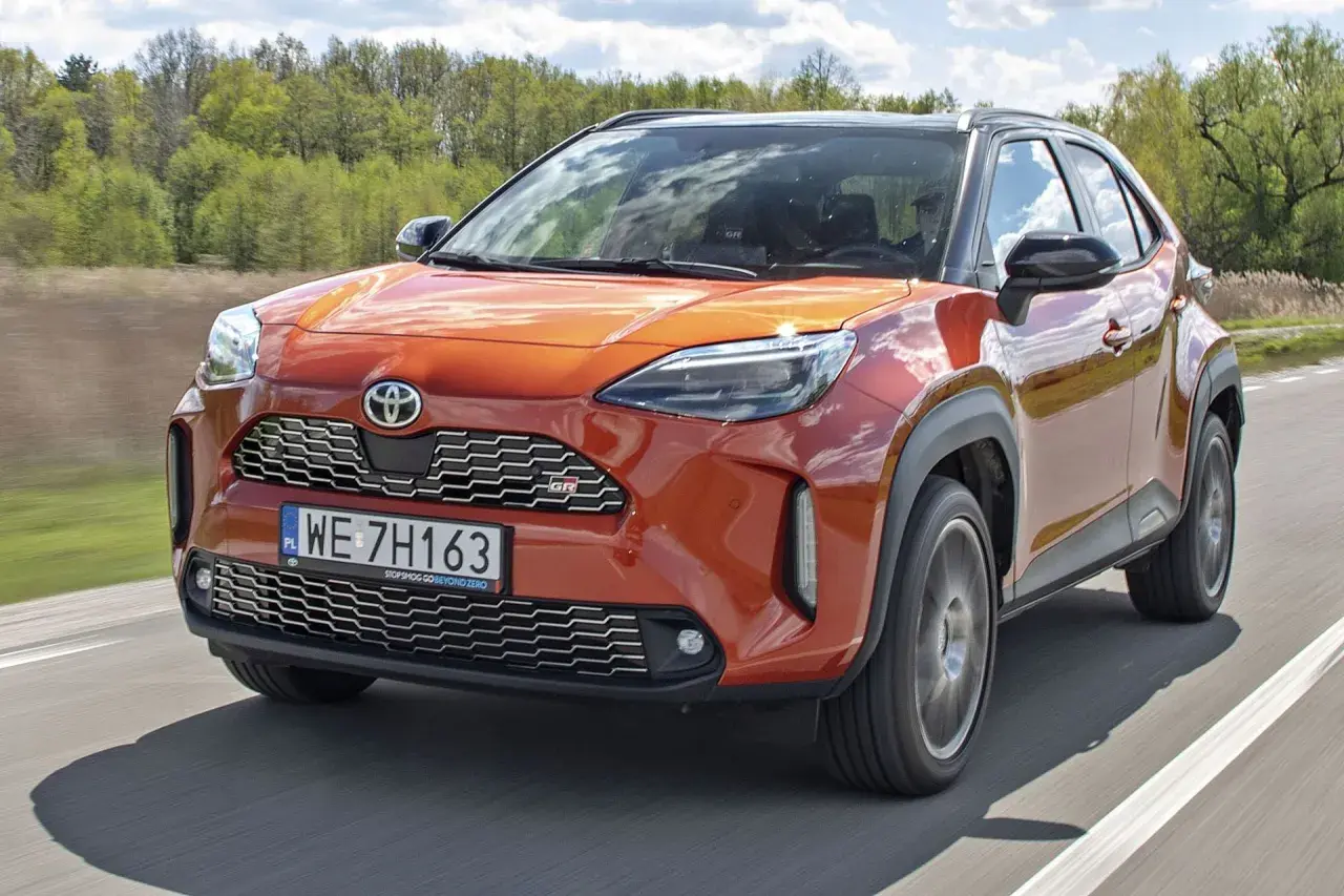 Pomarańczowy Toyota Yaris GR Sport na drodze. Wiele pozytywnych toyota yaris opinie potwierdza jego sportowy charakter i atrakcyjny wygląd.