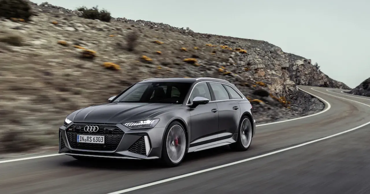 Szary Audi RS6 Avant pędzi po krętej drodze wśród skalistych wzgórz.