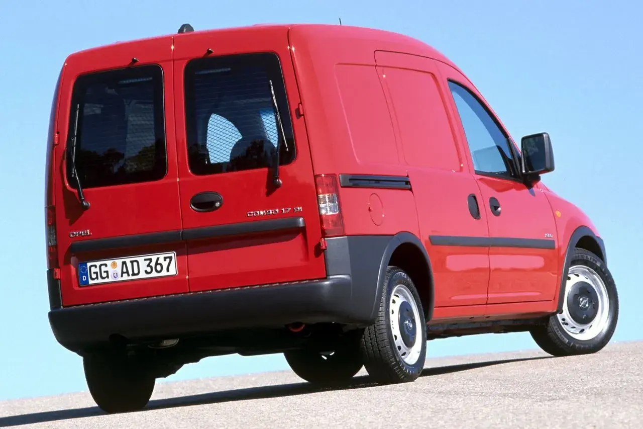 Czerwony Opel Combo C z przyciemnianymi tylnymi szybami i kratką ochronną.