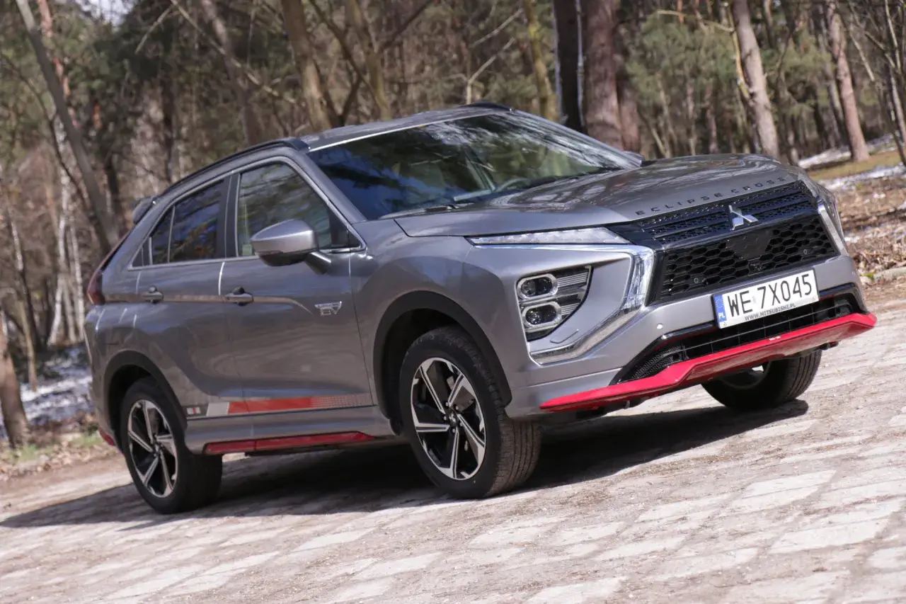 Szary Mitsubishi Eclipse Cross EV na leśnej drodze. Wiele pozytywnych mitsubishi eclipse cross opinie potwierdza jego wszechstronność.