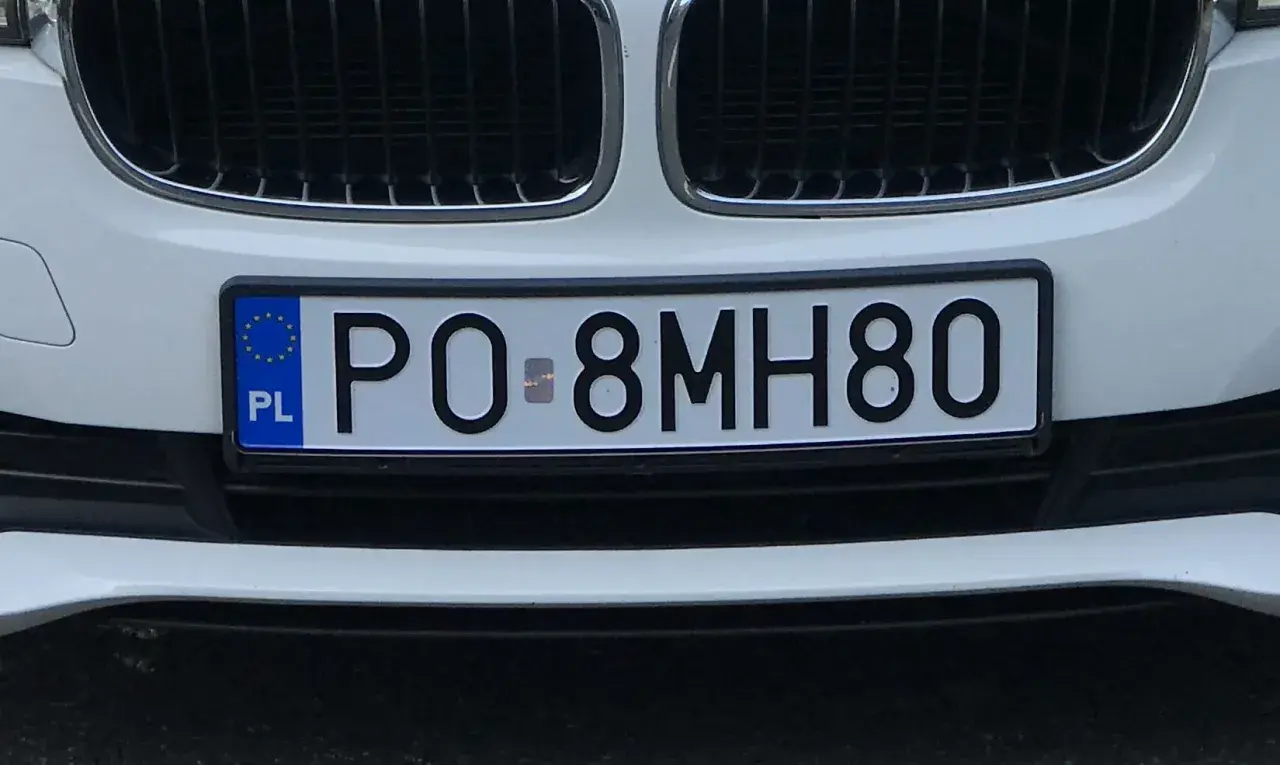 Biały samochód z tablicą rejestracyjną PO-8MH80.