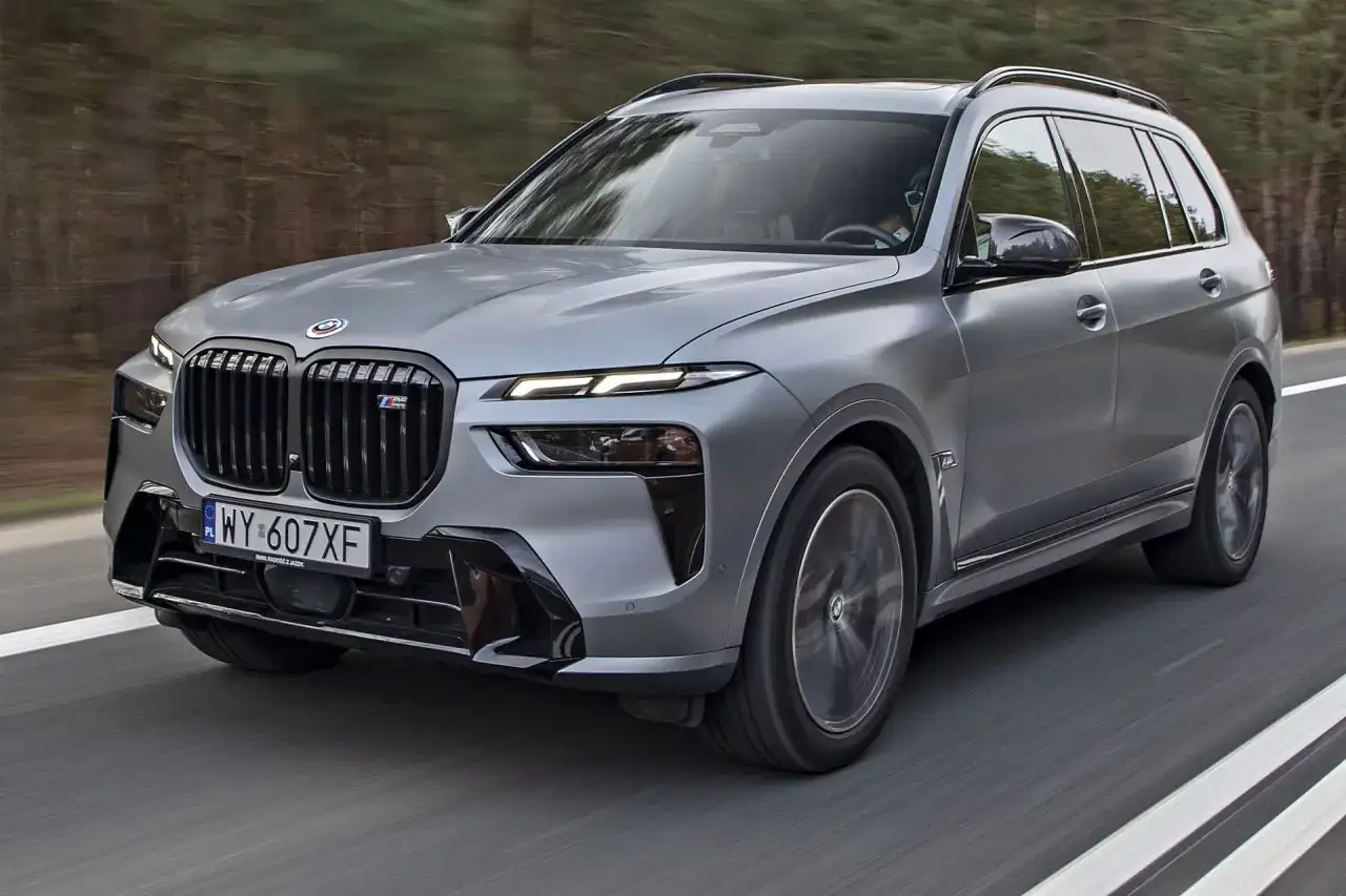 Szary BMW X7 M Sport pędzi po drodze. Sprawdź aktualną bmw x7 cena i dowiedz się więcej o tym luksusowym SUV-ie.