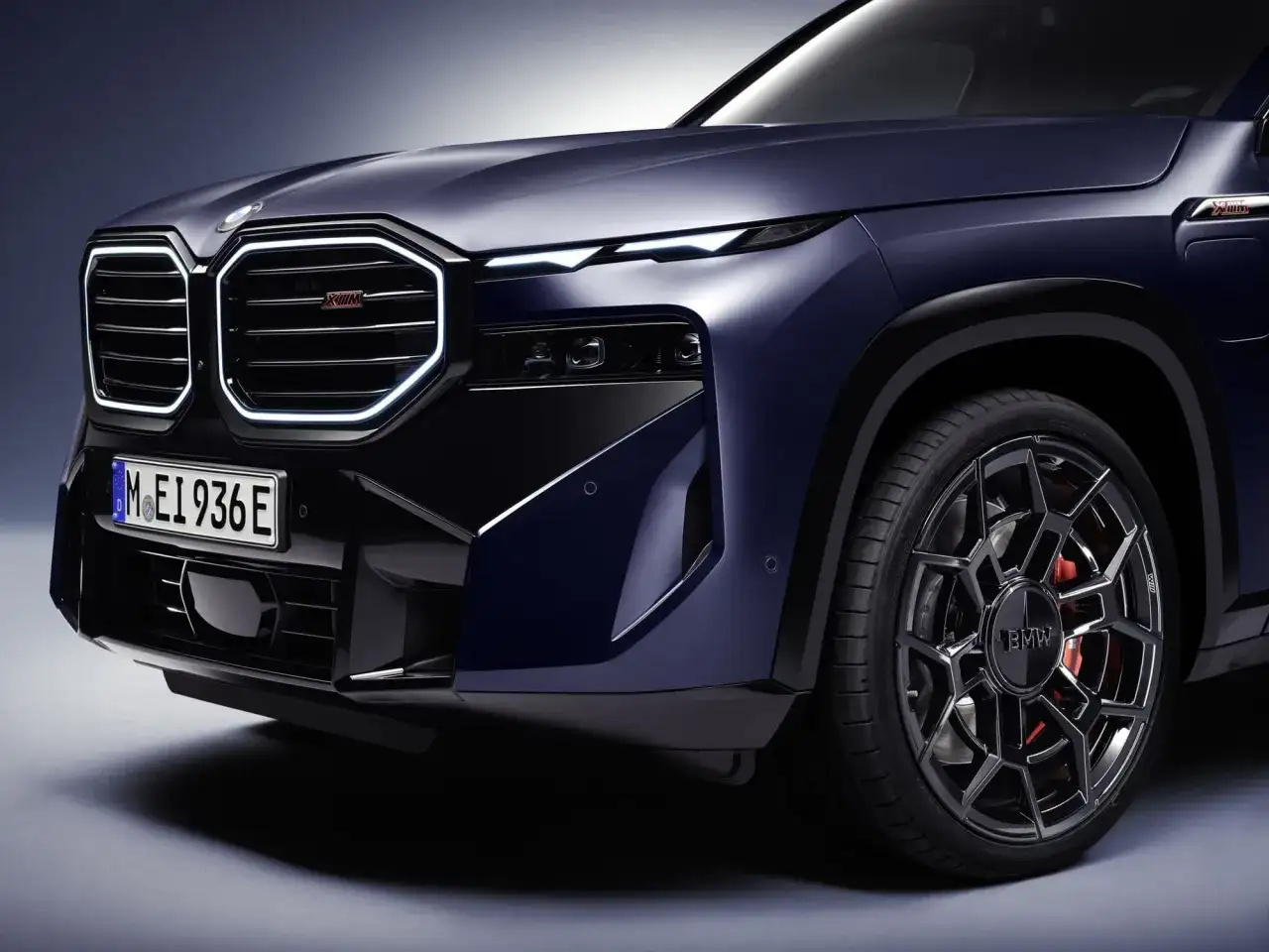 Elegancki, ciemnoniebieski BMW XM z podświetlaną atrapą chłodnicy i sportowymi felgami. Sprawdź BMW XM cena i możliwości tego SUV-a.