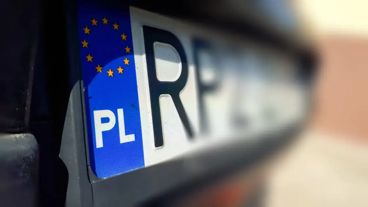 Zbliżenie na polską tablicę rejestracyjną z symbolem Unii Europejskiej. Litery "PL" i fragment numeru rejestracyjnego są wyraźne.