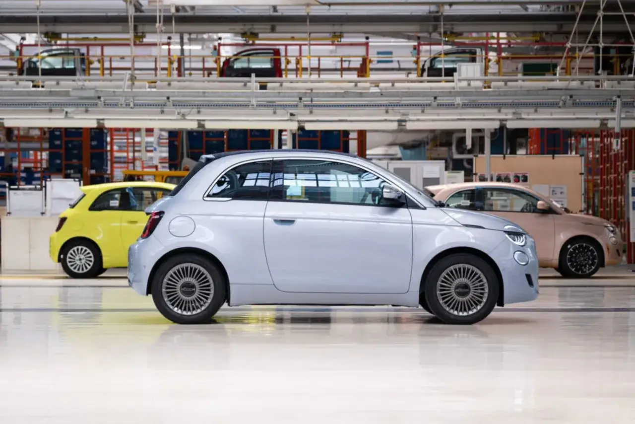 Nowe Fiat 500 w różnych kolorach na linii produkcyjnej. Wiele osób chwali sobie te auta, a opinie o nich są bardzo pozytywne.