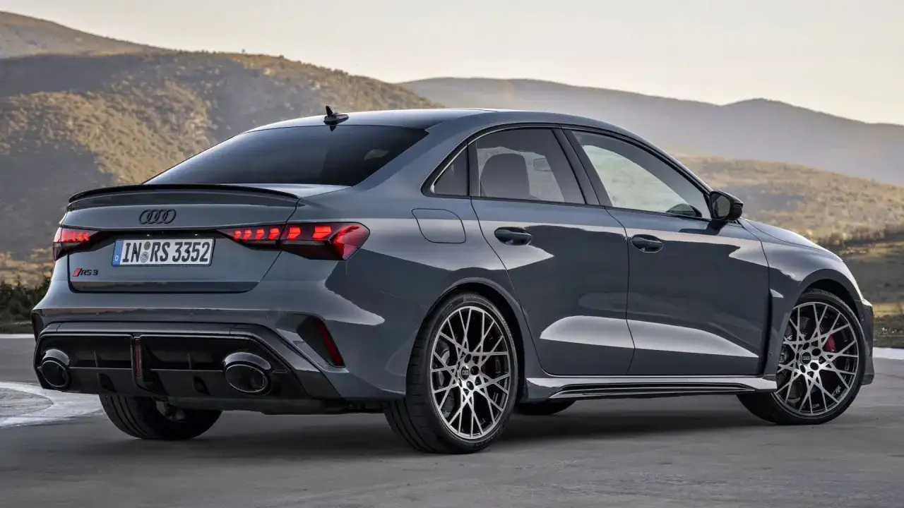 Szary Audi RS3 sedan z charakterystycznym spoilerem i podwójnymi końcówkami wydechu. Sprawdź aktualną audi rs3 cena.