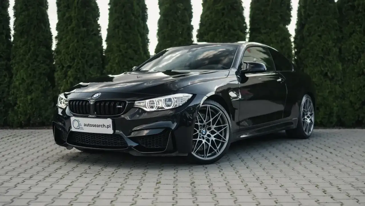 Czarny BMW M4 na tle zielonych drzew. Sprawdź aktualną bmw m4 cena i ofertę na autosearch.pl.