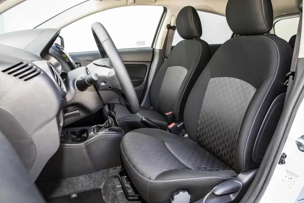 Wnętrze Mitsubishi Space Star. Fotele z czarno-szarym wzorem, kierownica i dźwignia zmiany biegów. Wiele osób szuka mitsubishi space star opinie.