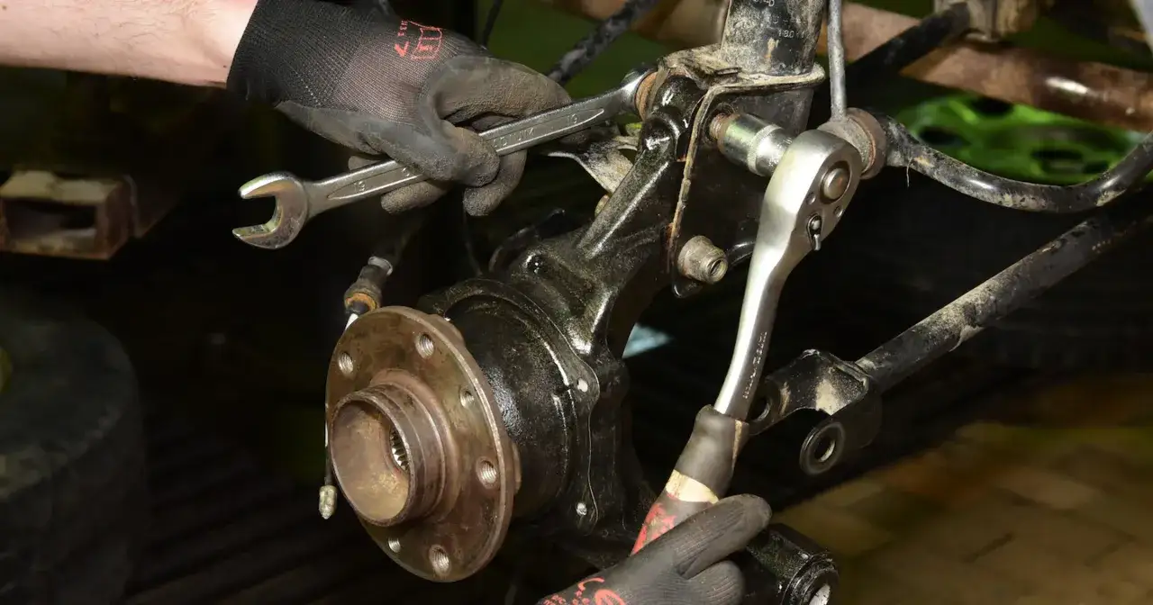 Mechanik dokręca śruby przy piaście, gdzie znajduje się łożysko w kole.