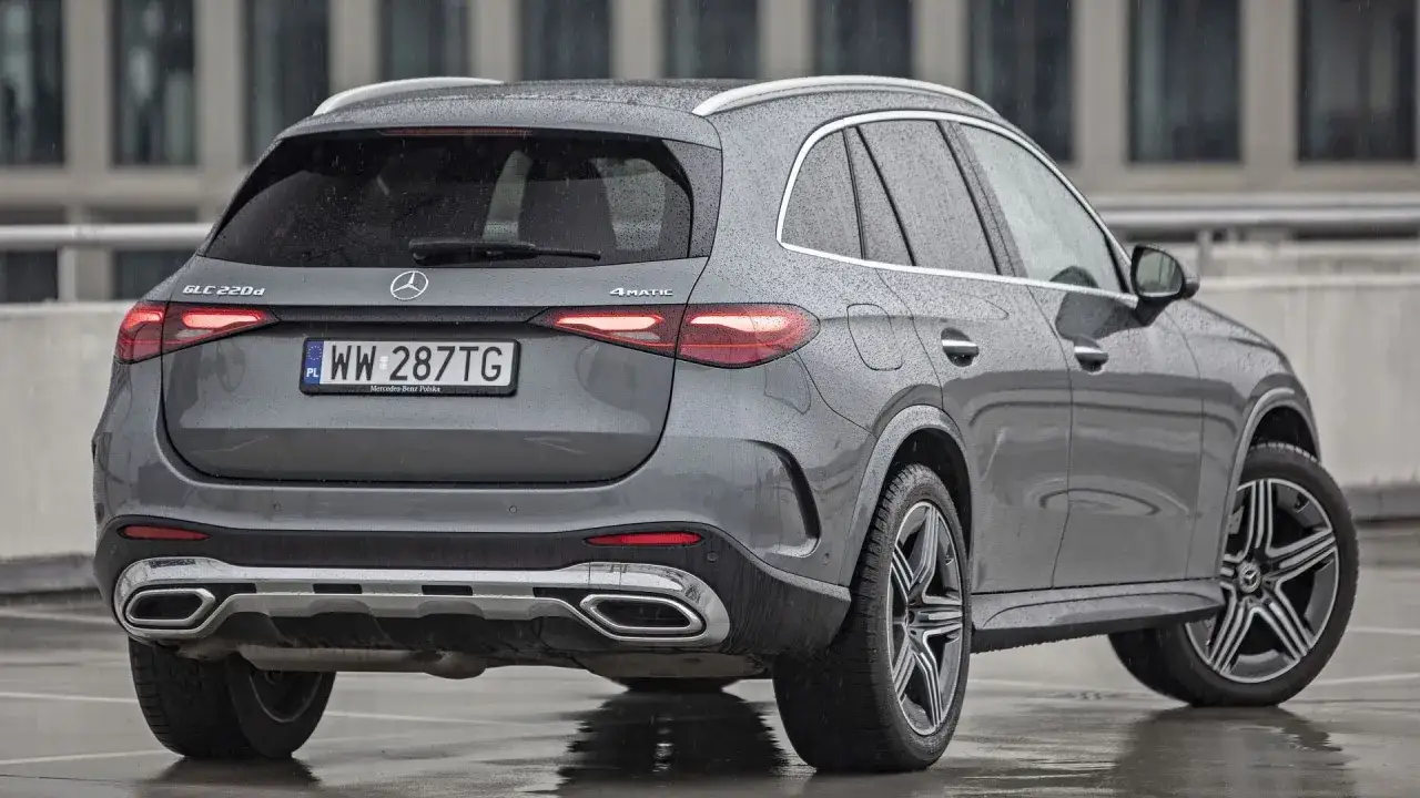 Szary Mercedes GLC 220d 4Matic na mokrym parkingu. Wiele osób szuka mercedes glc opinie przed zakupem.