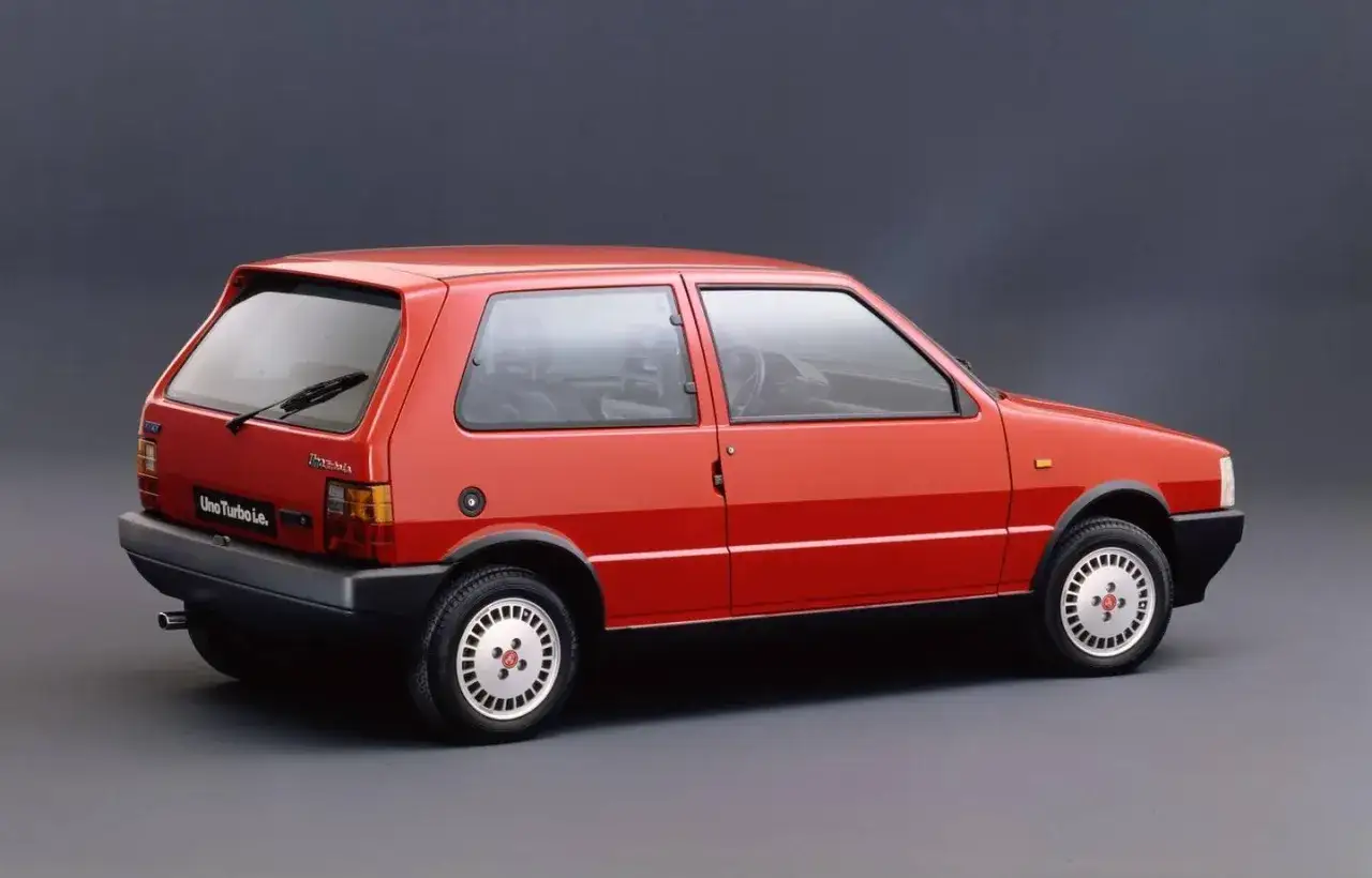 Czerwony Fiat Uno Turbo i.e. z lat 80. na szarym tle.
