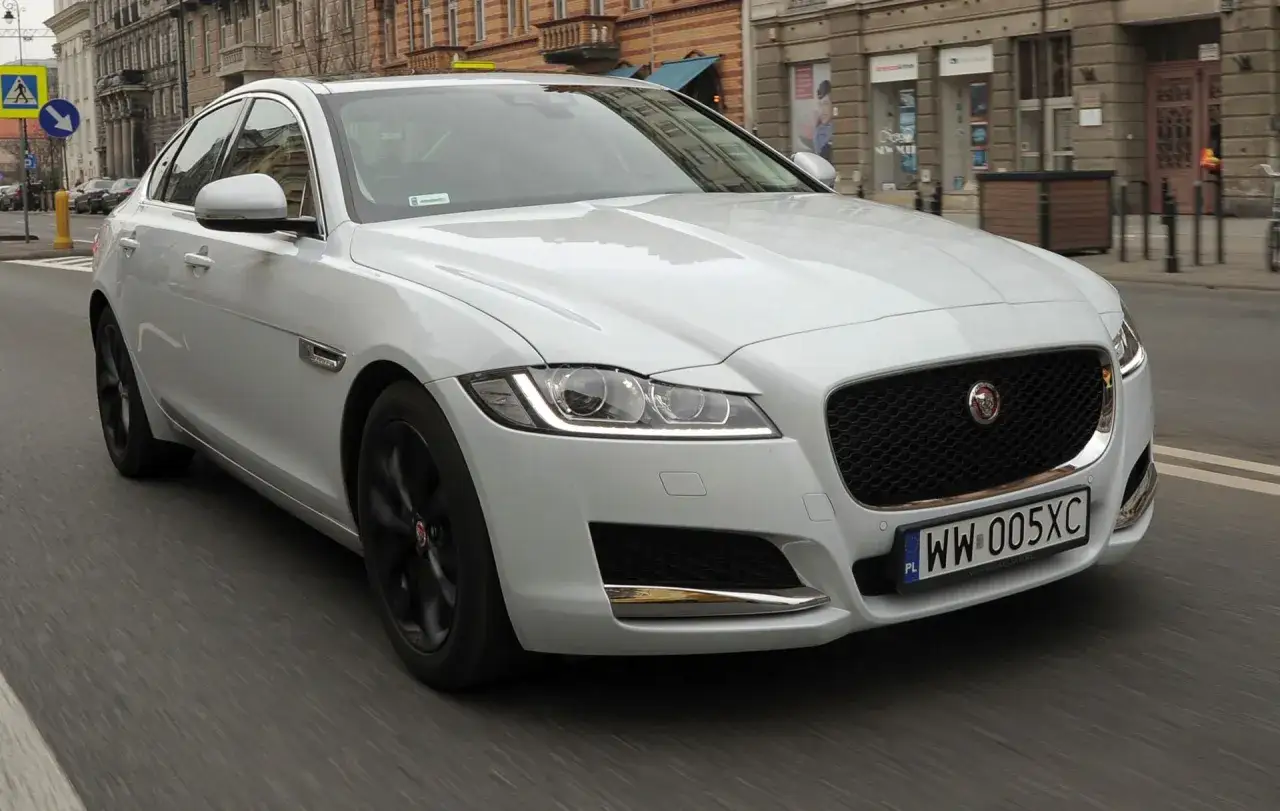 Biały Jaguar XF na ulicach miasta. Wiele osób chwali sobie ten model, a opinie o Jaguar XF są zazwyczaj pozytywne.